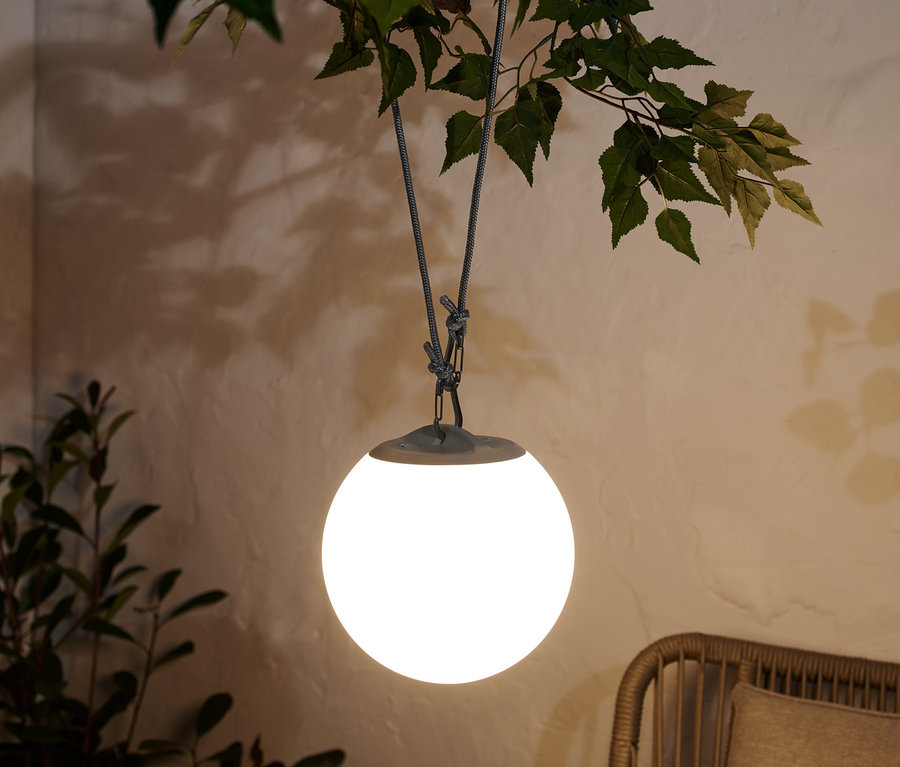 Akumulatorowa lampa wisząca LED zwisa z gałęzi drzewa.