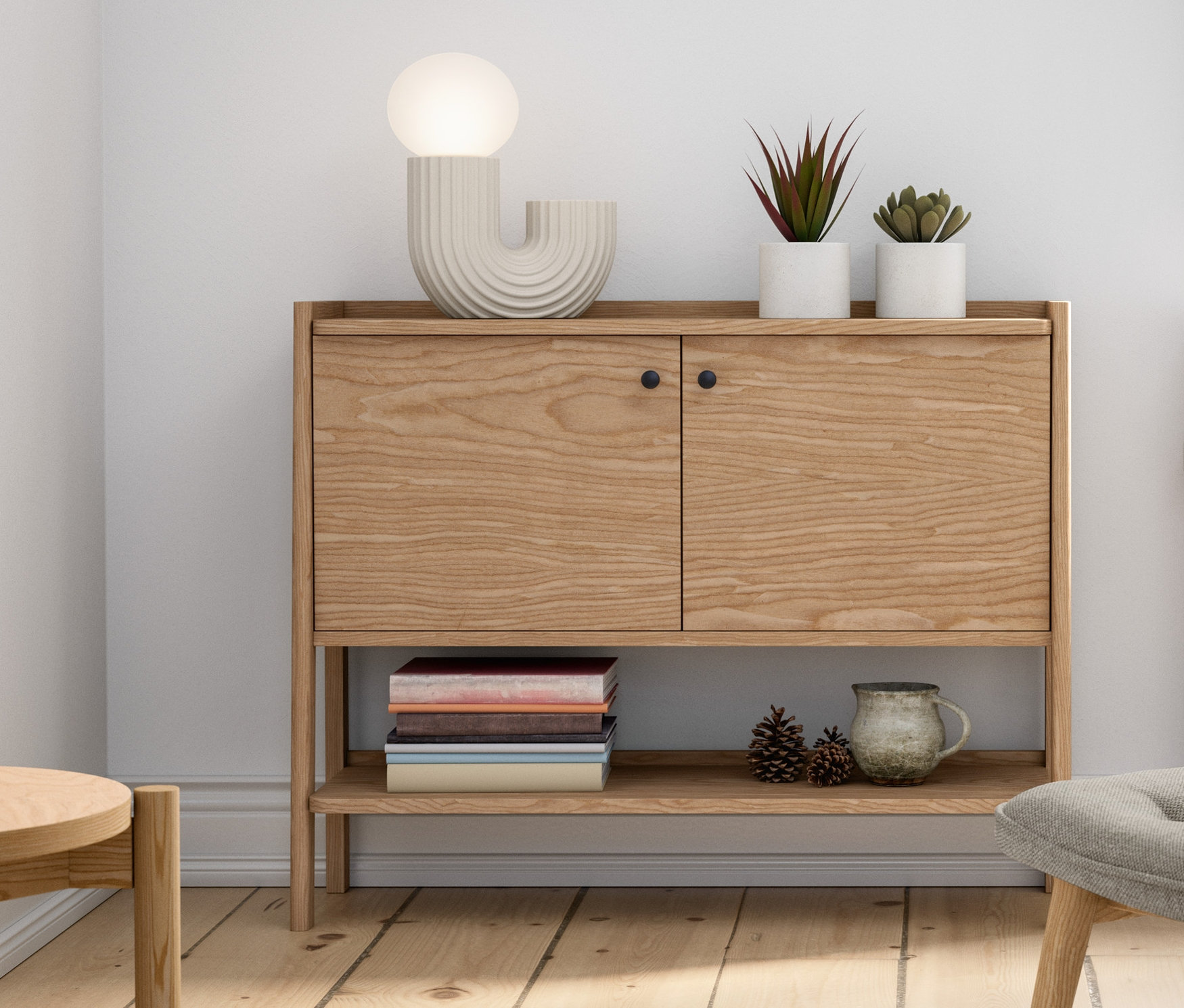 Wnętrze z drewnianą szafką, lampką stołową LED, fotelem z podnóżkiem, roślinami doniczkowymi i dekoracjami.