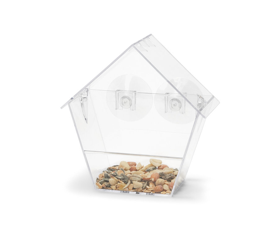 Przezroczysty karmnik dla ptaków na okno wypełniony ziarnami.