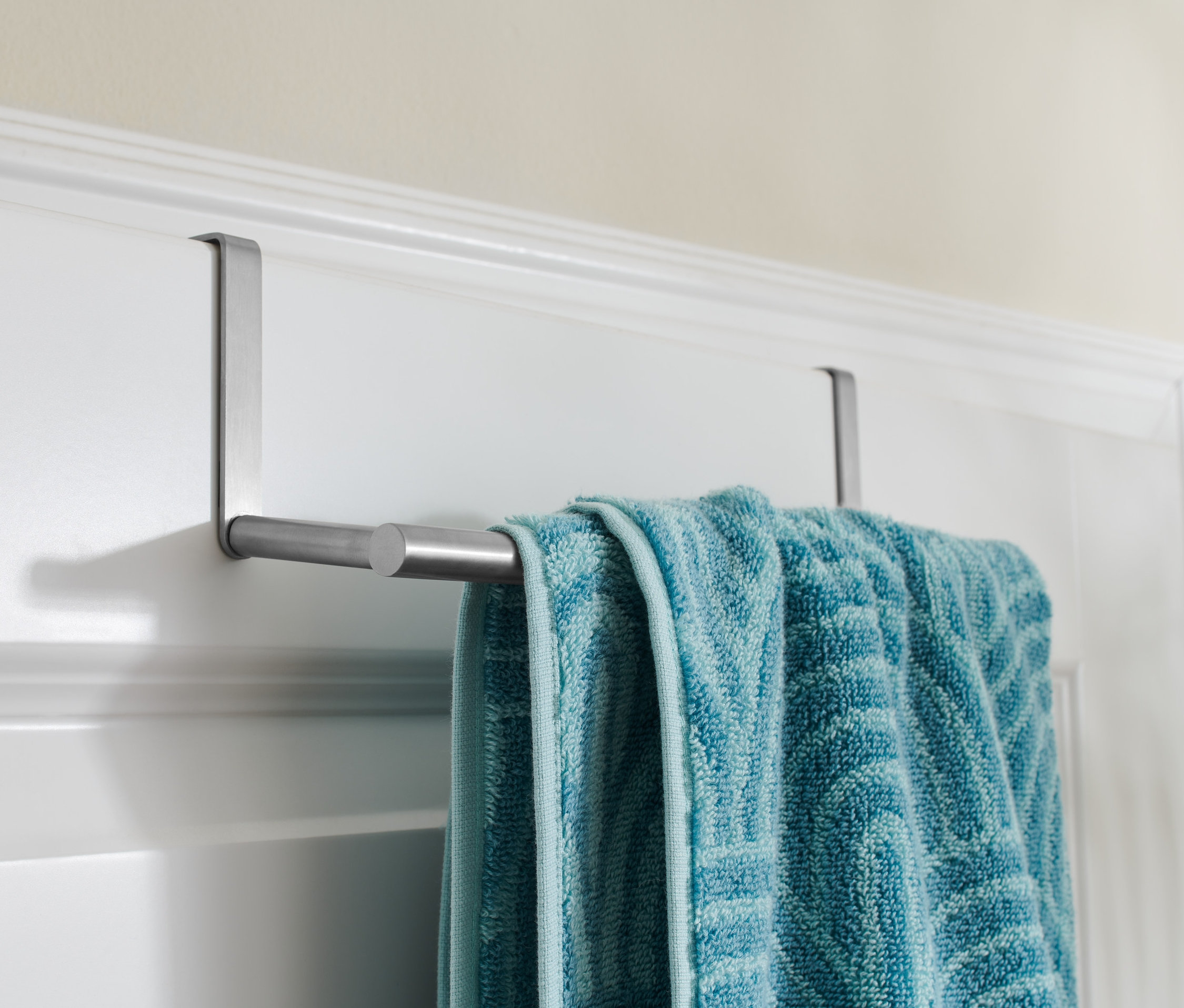 Niebieski ręcznik wisi na wieszaku na drzwi.