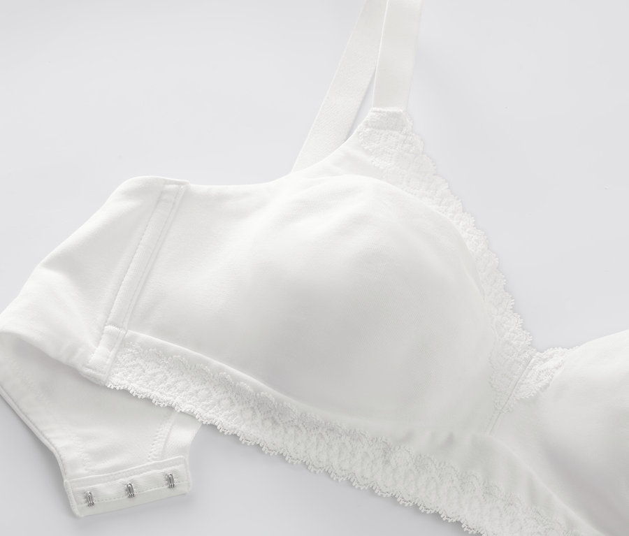 Detal białego, miękkiego biustonosza z koronką.