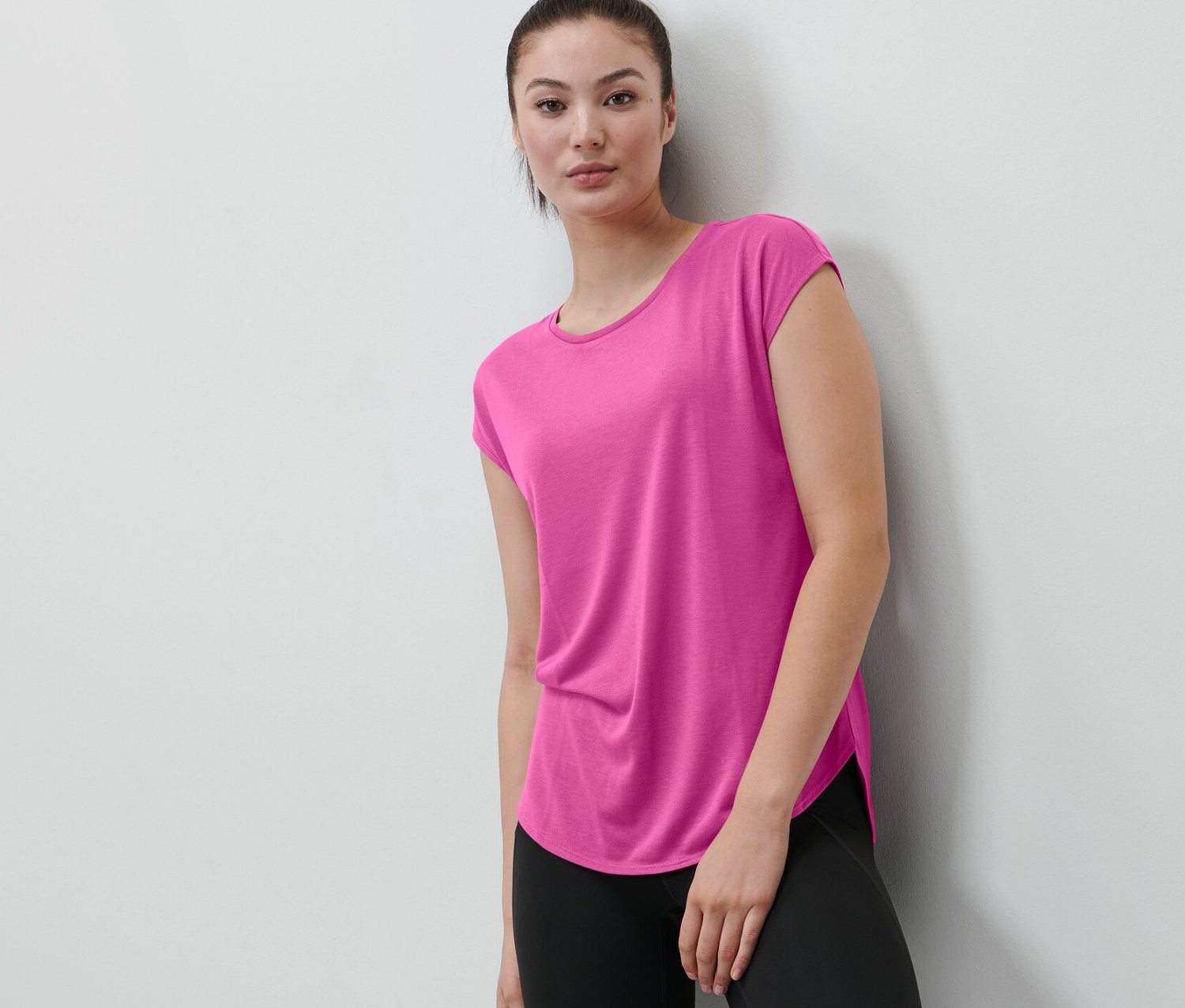 Kobieta ma na sobie różową koszulkę sportową.