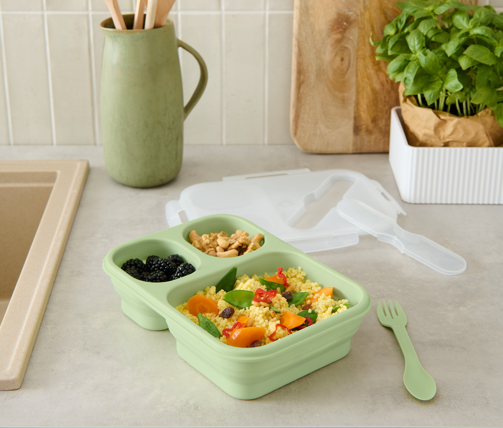 Zielony składany pojemnik spożywczy z jedzeniem na blacie kuchennym.