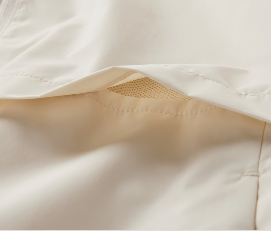 Zbliżenie na kremową, wiatroszczelną kurtkę do biegania.