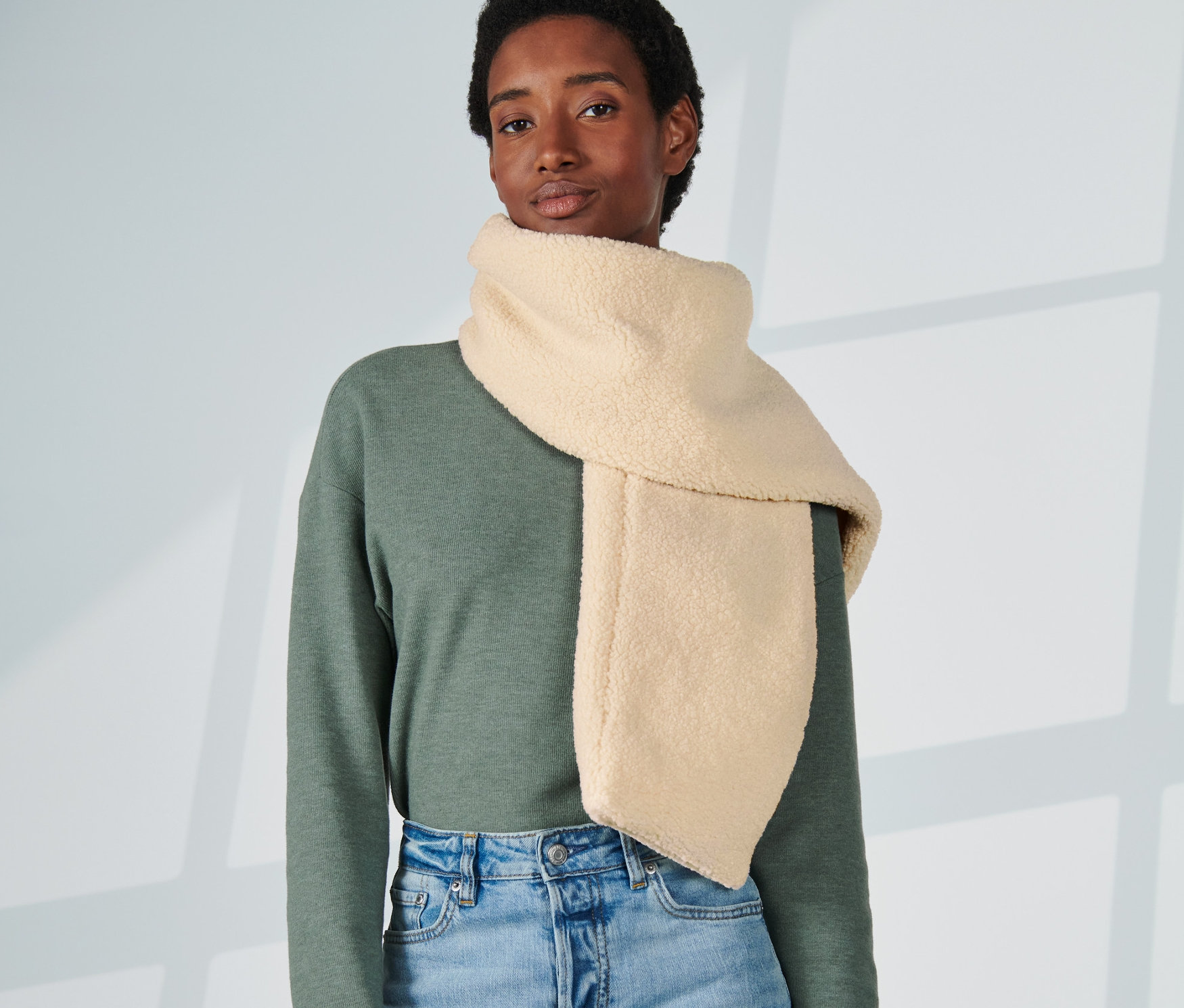 Kobieta ma na sobie kremowy pluszowy szalik.