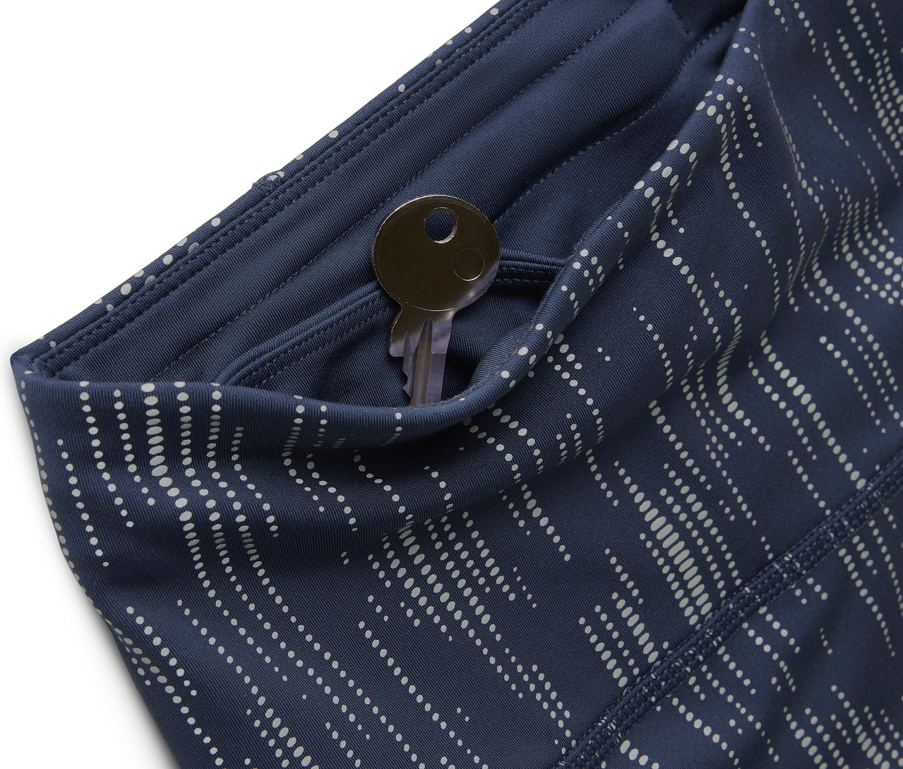 Zbliżenie na niebieskie, wzorzyste legginsy z kluczem w kieszeni.