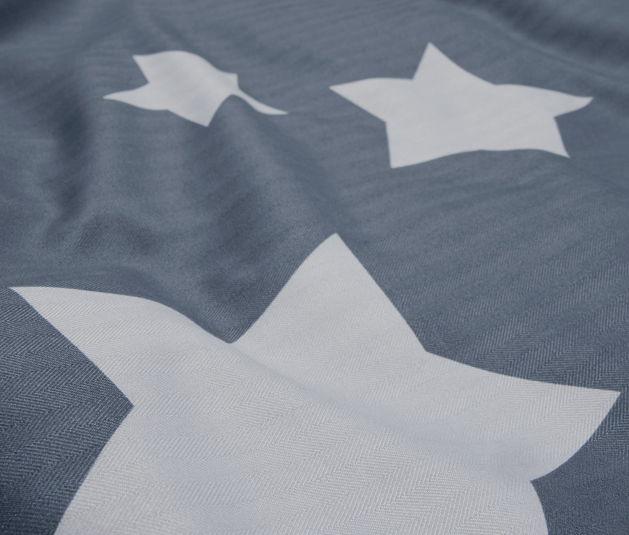 Szczegółowe ujęcie szarej tkaniny z białymi gwiazdami.