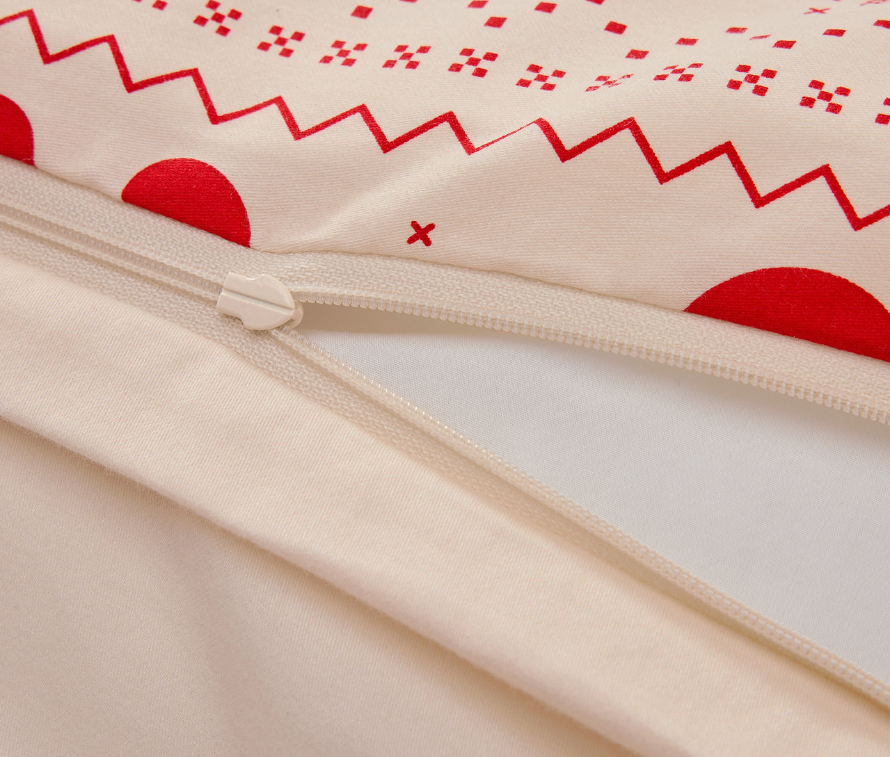 Zbliżenie na bawełnianą poszwę na kołdrę z czerwonym geometrycznym wzorem i zamkiem błyskawicznym.