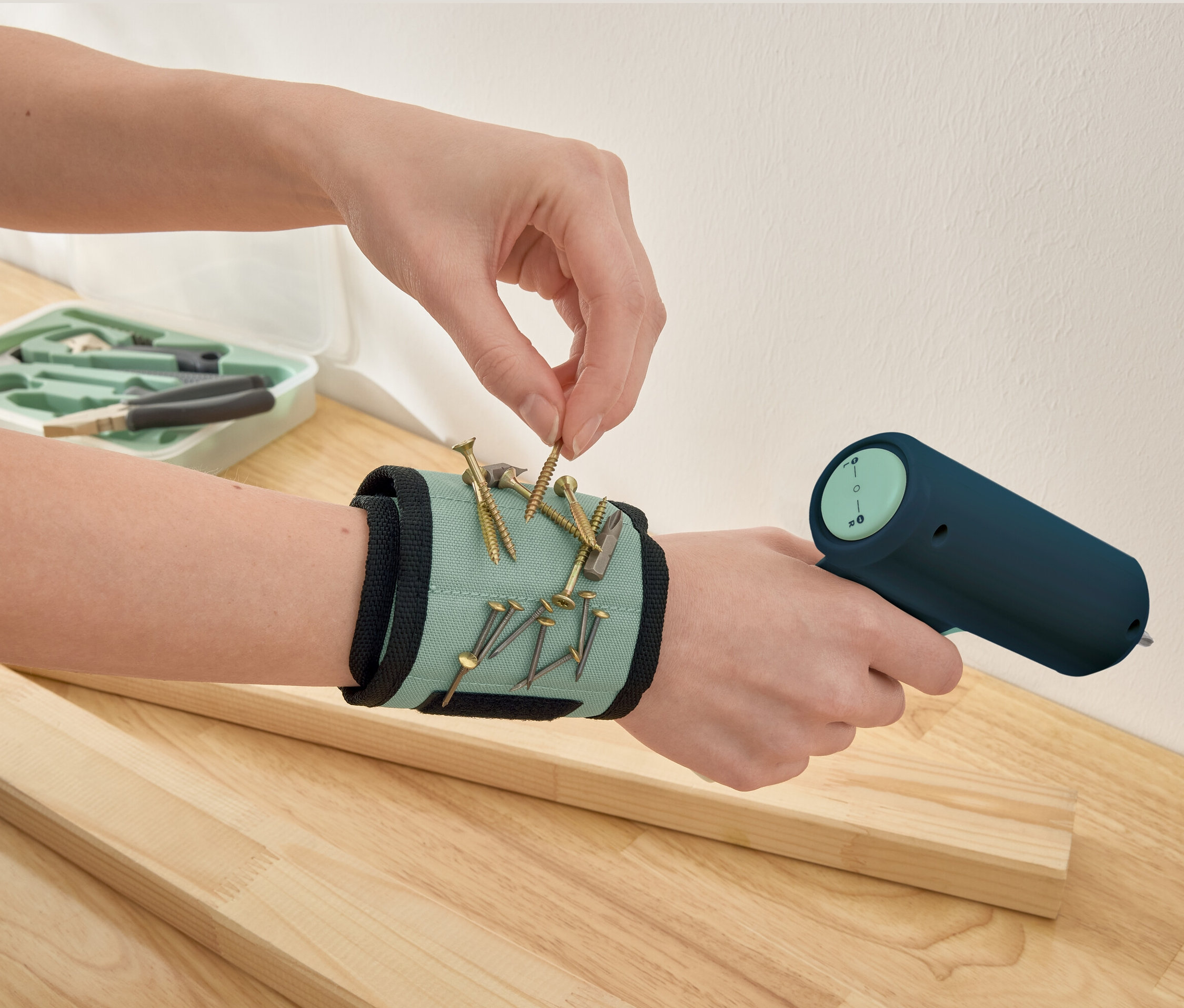 Ręka podnosi śrubę z magnetycznej opaski na nadgarstek.
