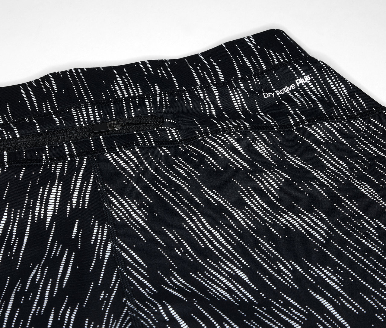 Zbliżenie na czarne legginsy we wzór z białych linii i kieszenią na zamek błyskawiczny.