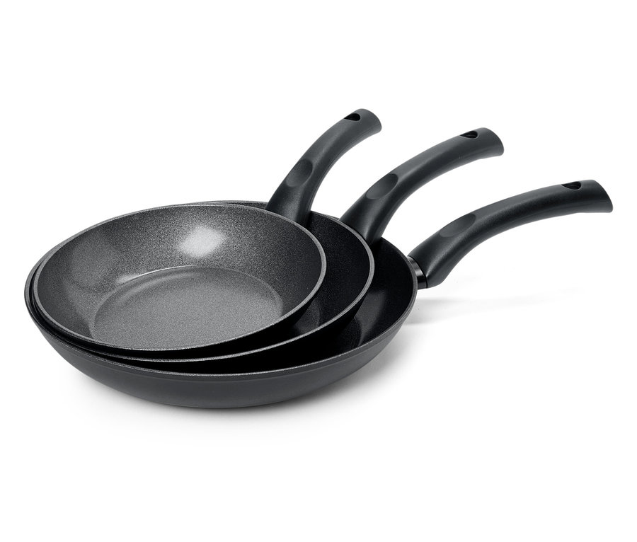 Trzy czarne patelnie o różnych rozmiarach ułożone jedna na drugiej.