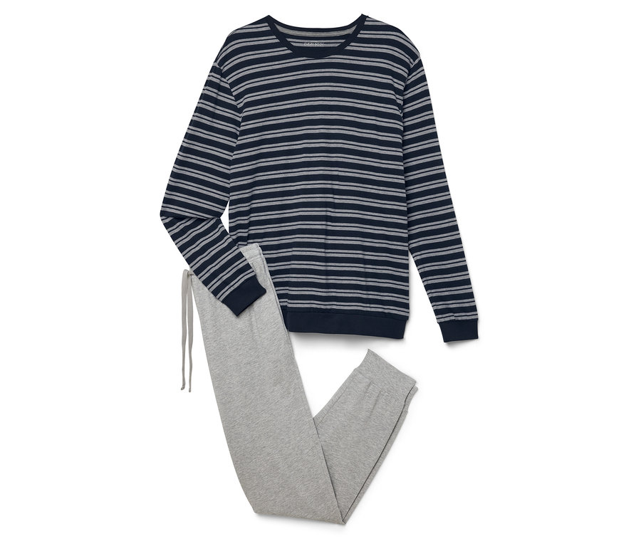 Na sobie leżą bluzka w paski z długim rękawem i szare spodnie dresowe.