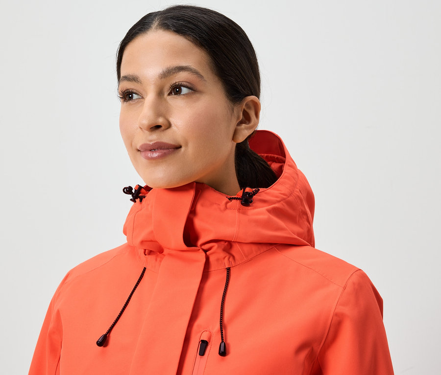 Portret kobiety w koralowej kurtce z kapturem.