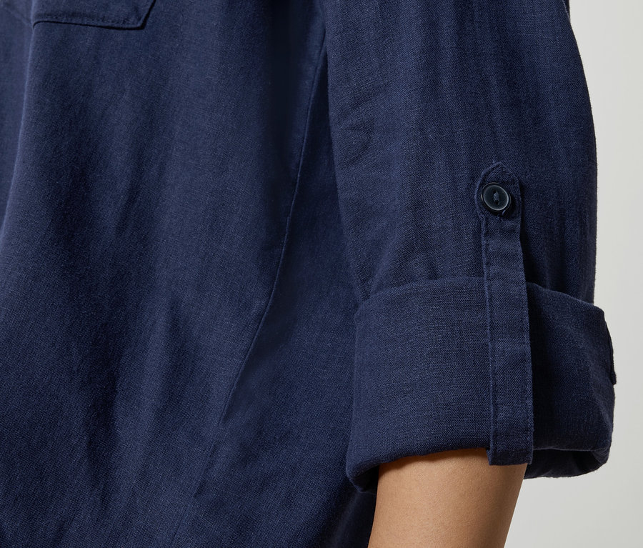 Zbliżenie na granatową lnianą koszulę z podwiniętymi rękawami i detalami z guzikami.