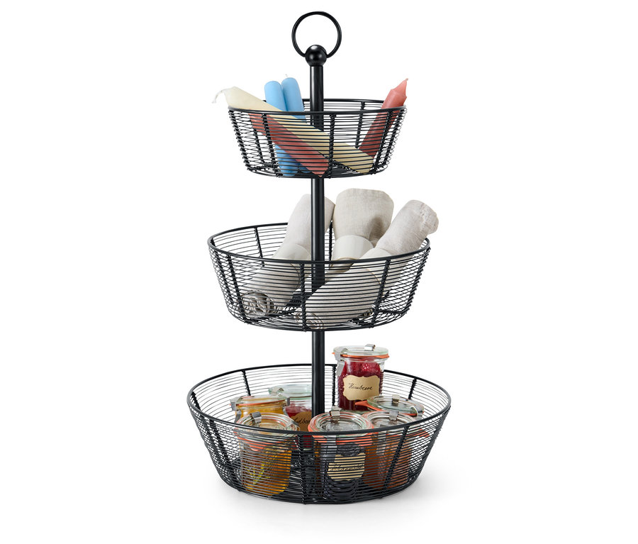 Trzypoziomowy, czarny druciany kosz zawiera świece, ścierki i słoiki.
