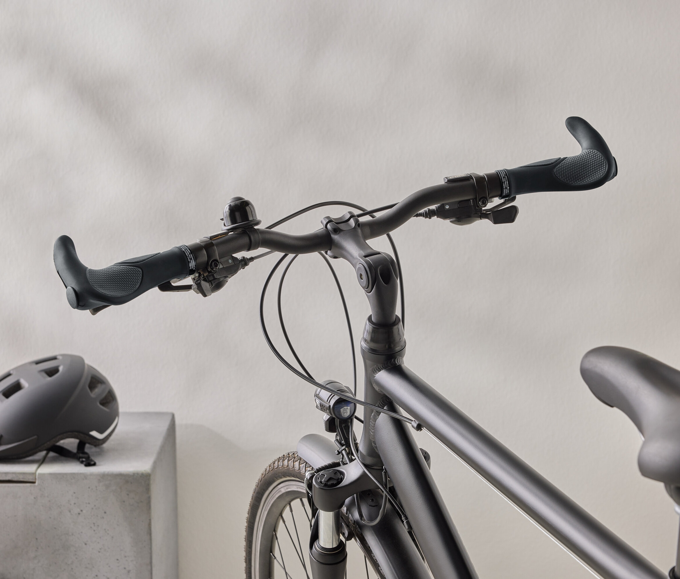 Zbliżenie matowego czarnego roweru z czarnym kaskiem na betonowej powierzchni w tle.