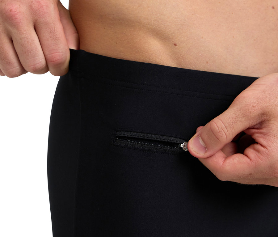 Mężczyzna otwiera zamek czarnych spodni.