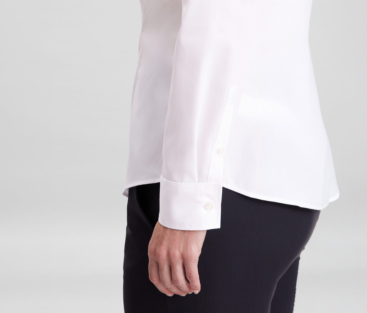 Osoba w białej bluzce Seidensticker Slim Fit non iron i czarnych spodniach, widoczny rękaw z mankietem.