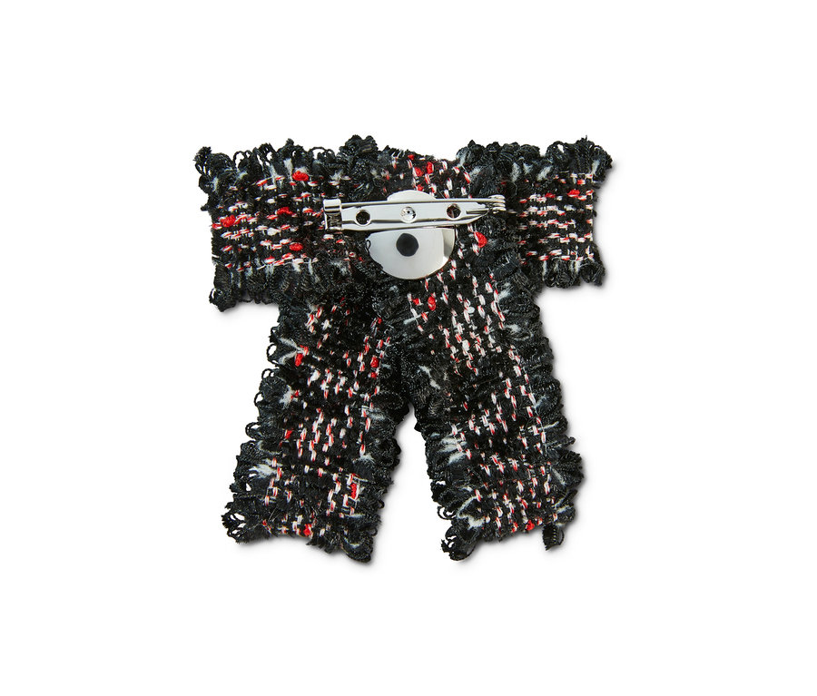 Zbliżenie na broszkę w kształcie kokardki z tweedu.