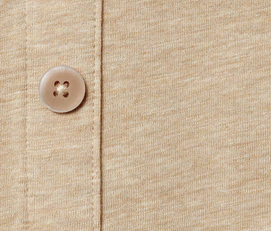 Zbliżenie na beżową koszulkę z plisą z guzikami.