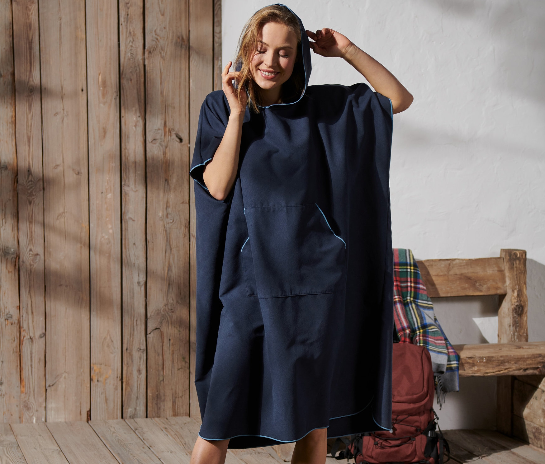 Kobieta poprawia kaptur na swoim niebieskim poncho kąpielowym.