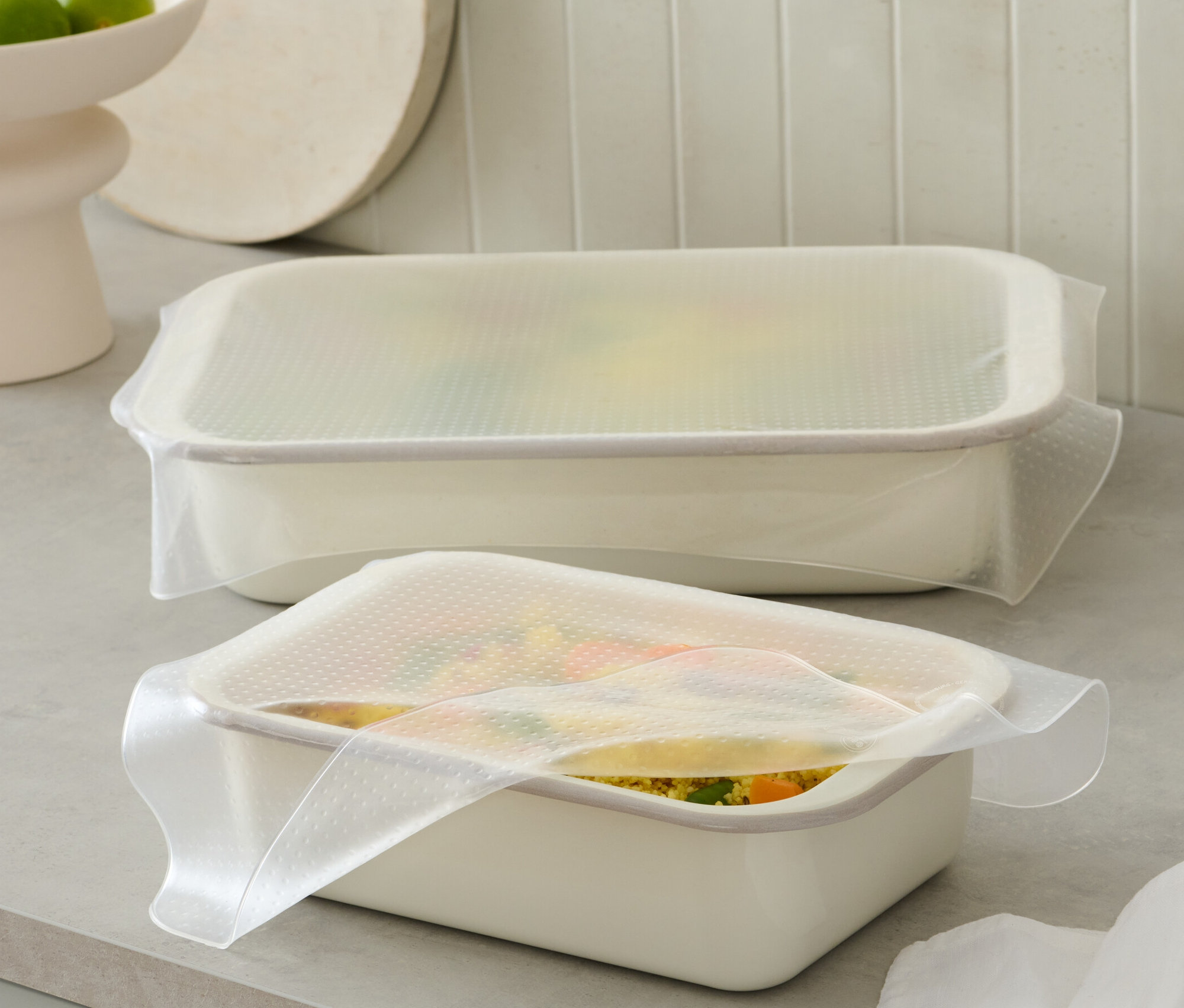 Dwa białe pojemniki przykryte są 2 arkuszami silikonowej folii do żywności.