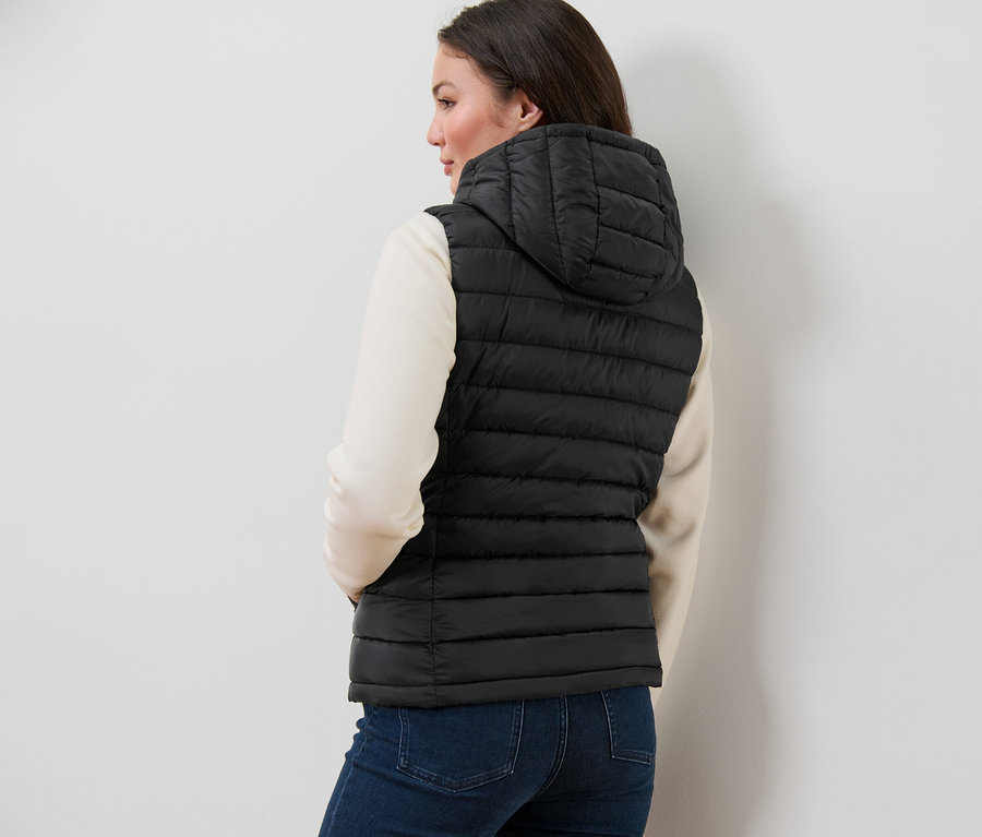 Kobieta ma na sobie pikowaną kamizelkę z kapturem.