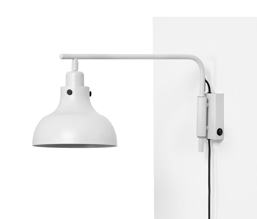 Lampa ścienna z odchylanym ramieniem z metalu zamocowana na białej ścianie.