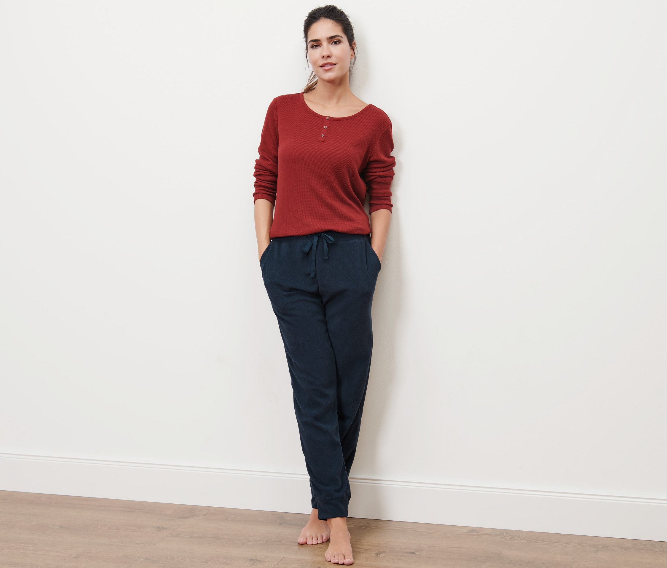 Kobieta pozuje z rękami w kieszeniach niebieskich spodni rekreacyjnych.