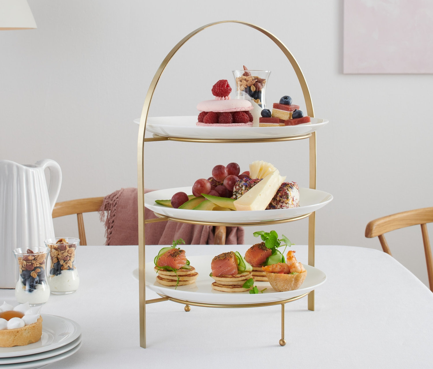 Trzypiętrowa patera z jedzeniem stoi na stole.