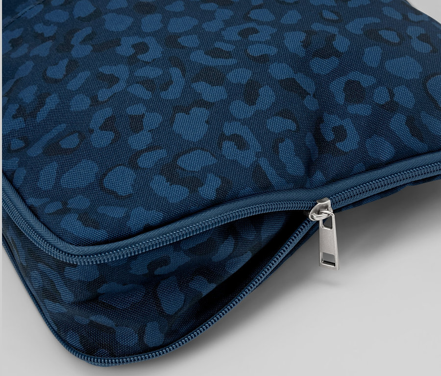 Zbliżenie na niebieską, wzorzystą torbę antykradzieżową na ramię ze srebrnym zamkiem błyskawicznym.