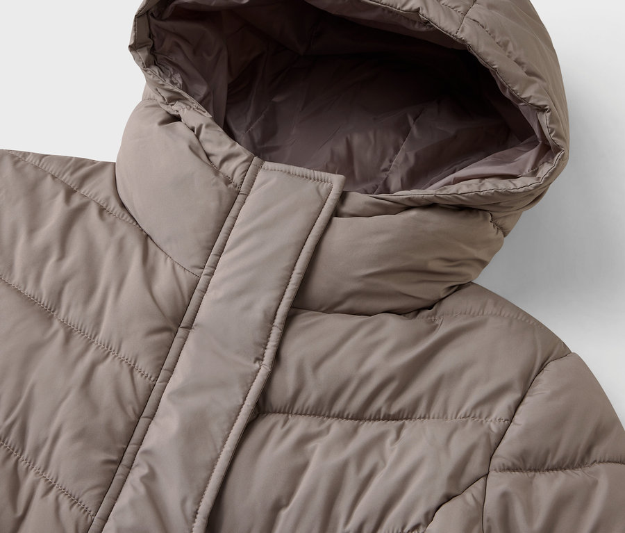 Szczegół beżowej kurtki puchowej z kapturem.