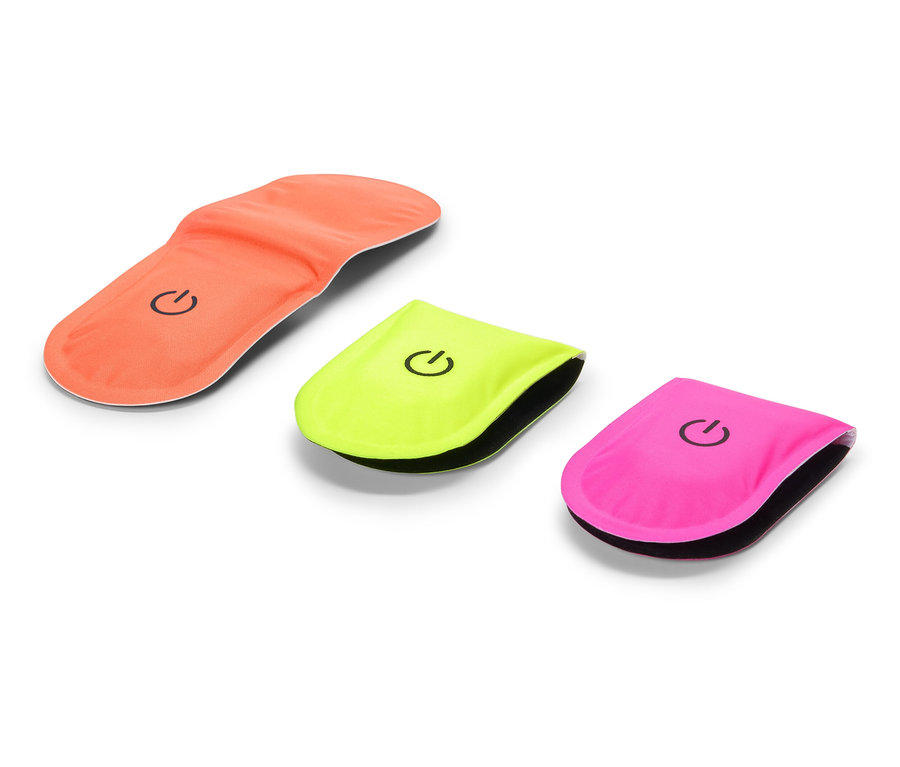 Pomarańczowa wkładka do butów leży obok żółtego i różowego światła odblaskowego.