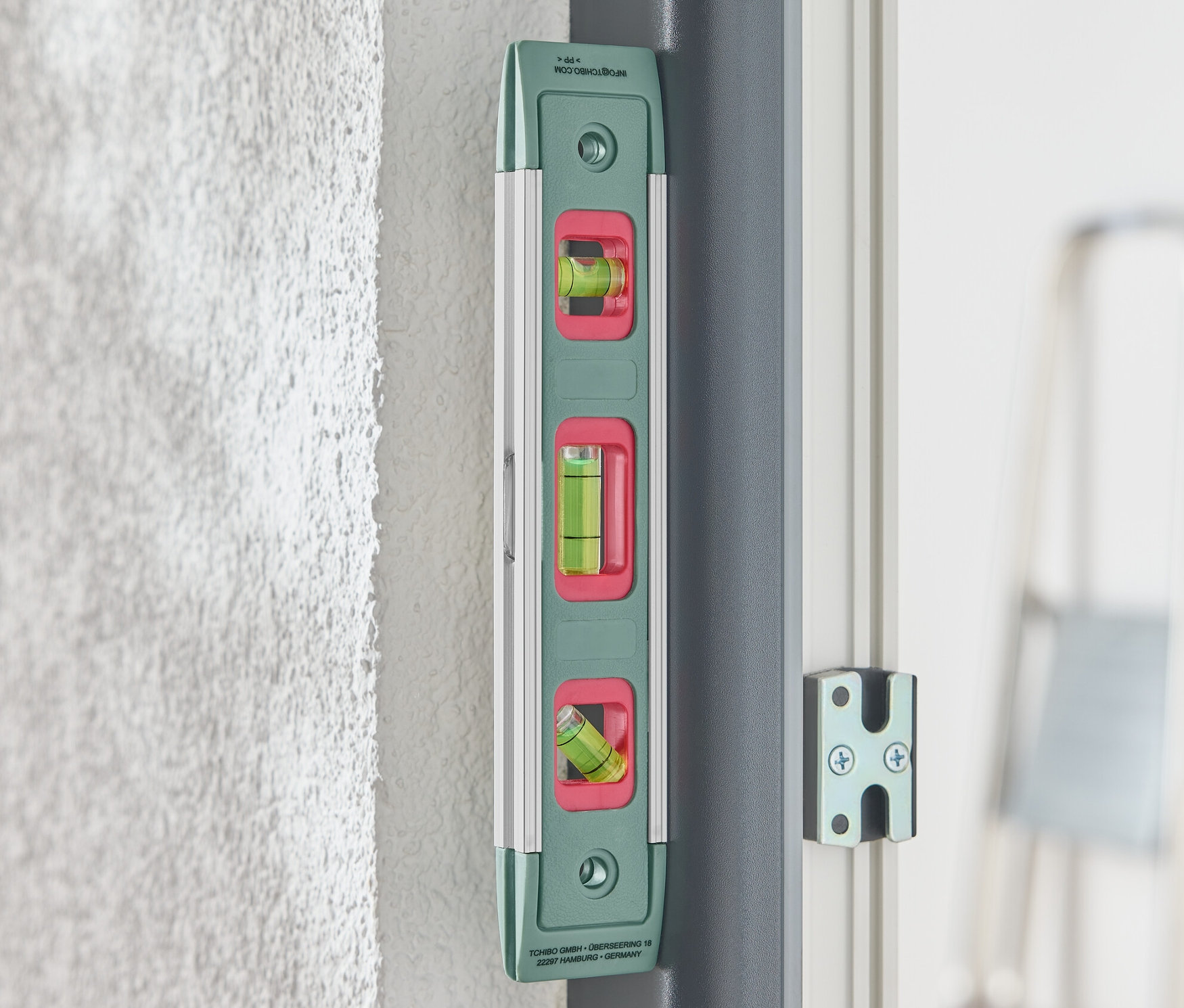 Zielona poziomica magnetyczna przymocowana do ściany.