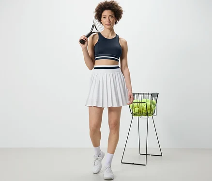 Kobieta trzyma rakietę tenisową i ma na sobie niebieską sportową braletkę „Crop Top”.