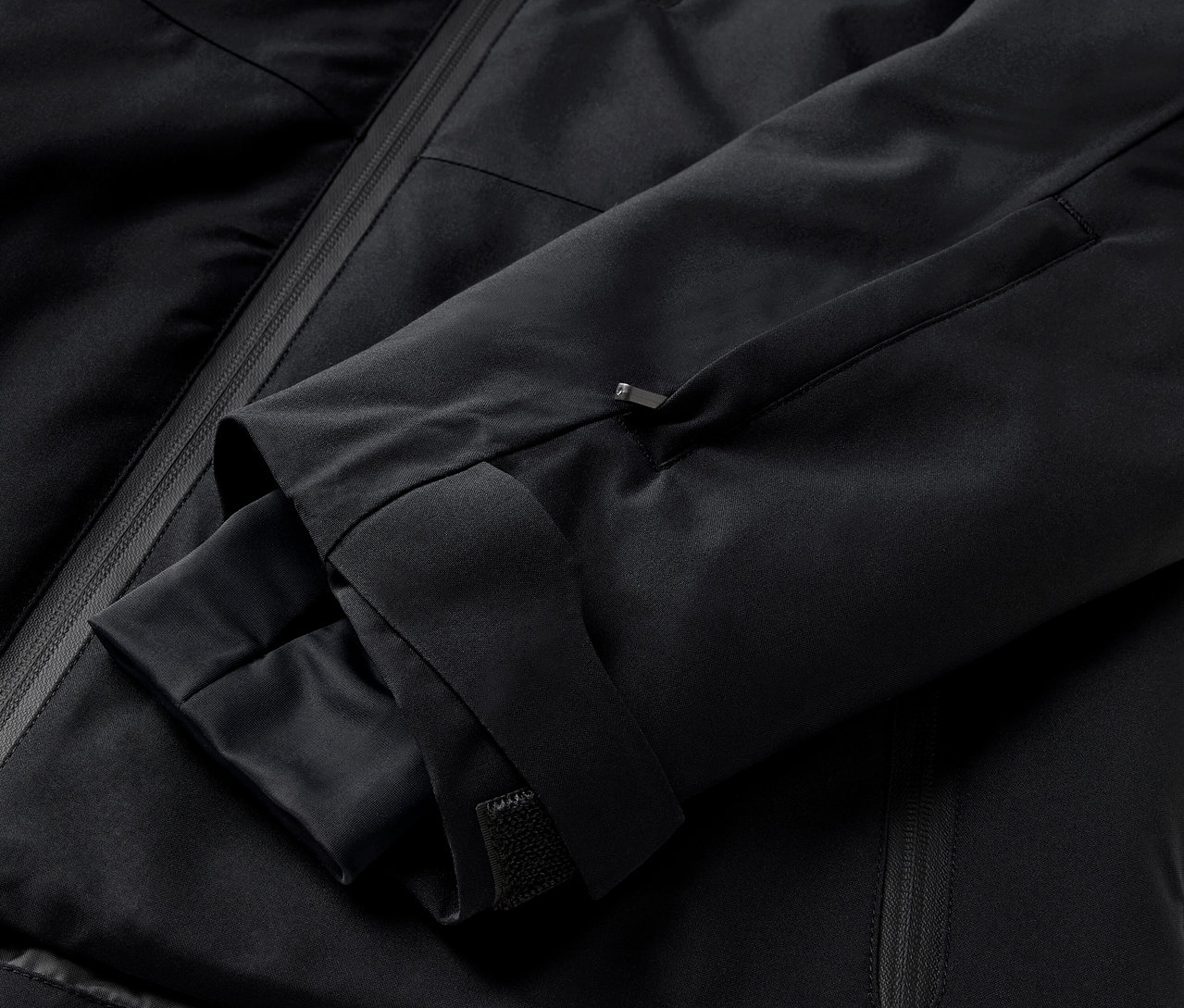 Szczegół czarnej kurtki z rękawem i kieszenią na zamek.