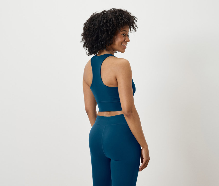 Kobieta patrzy przez ramię, ubrana w niebieski strój sportowy.