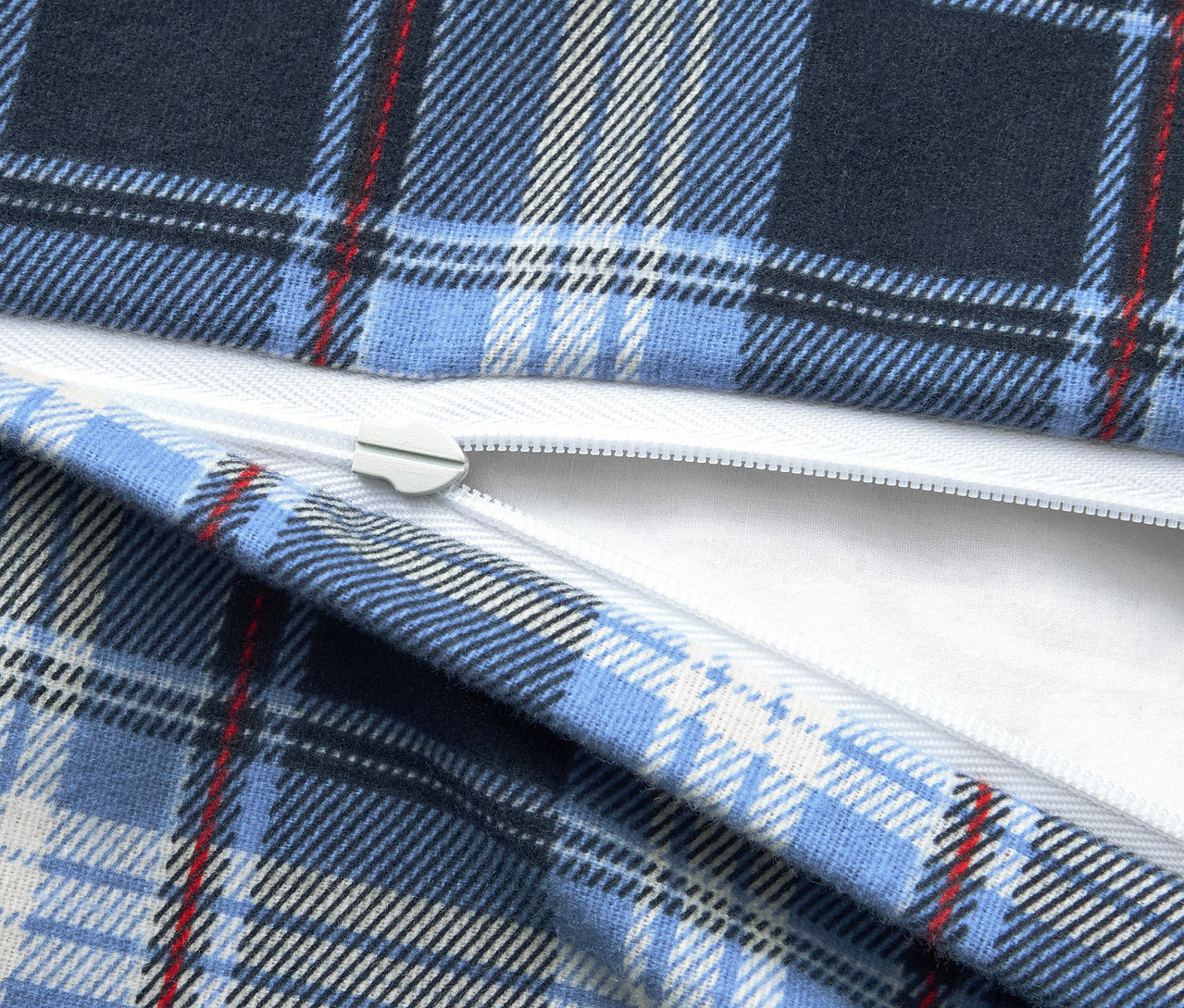 Szczegół niebieskiej tkaniny w kratę z białym zamkiem błyskawicznym.