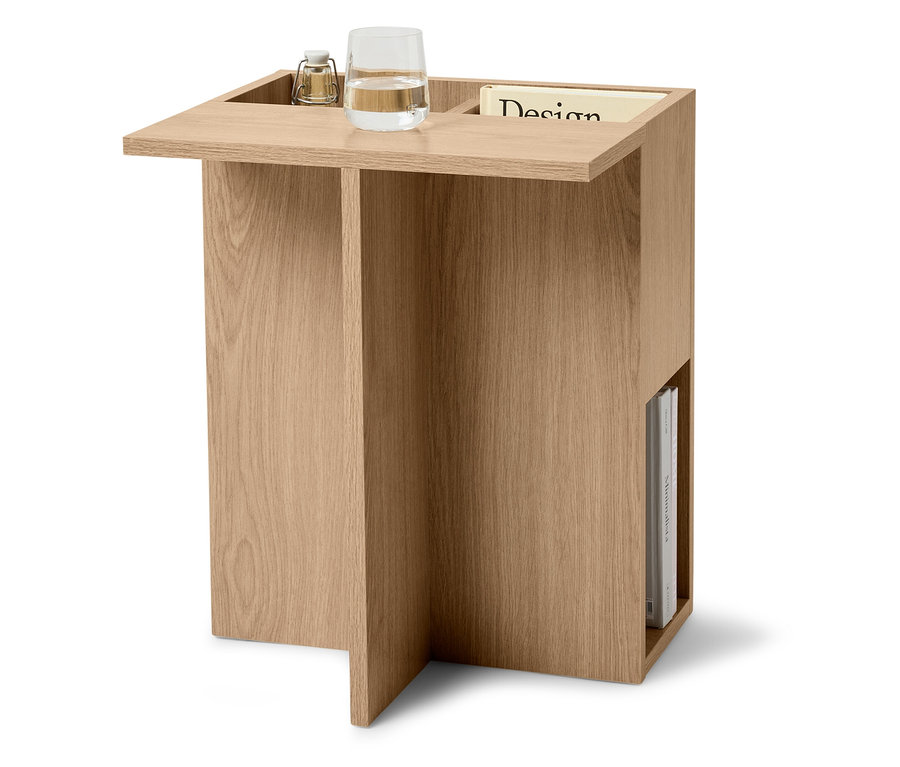 Stolik boczny z jasnego drewna ze szklanką wody, lampą i czasopismem.