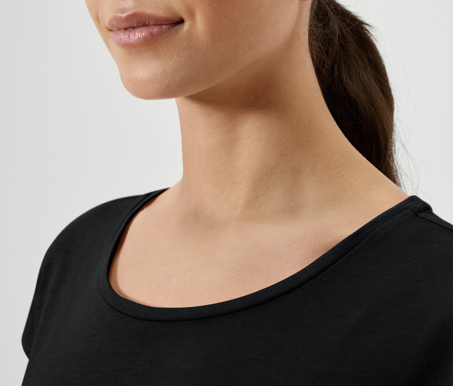 Zbliżenie na kobietę z brązowymi włosami związanymi w kucyk, ubraną w czarną koszulkę.