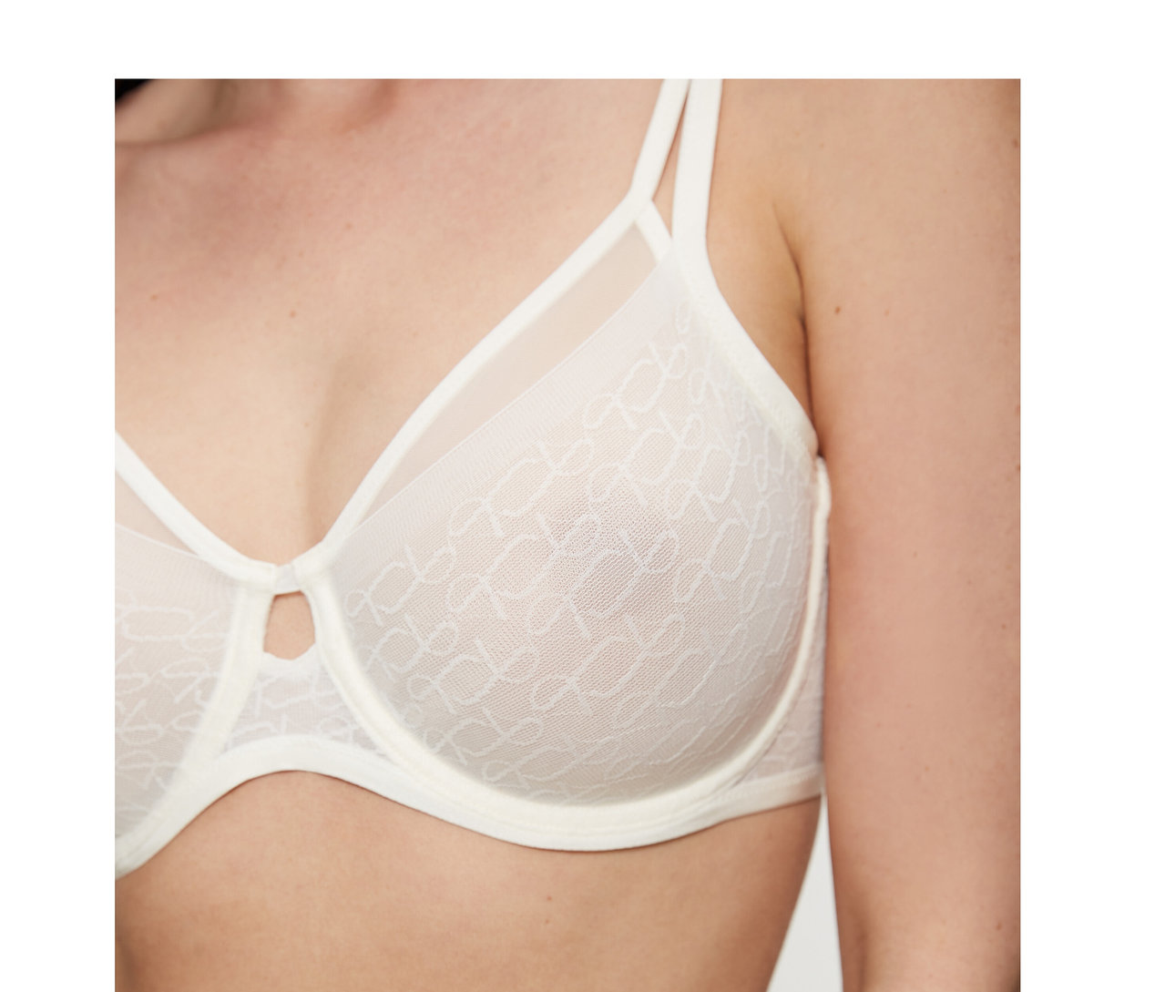 Kobieta ma na sobie biustonosz Triumph Signature Sheer Minimizer w kolorze ecru white, z wzorzystymi, prześwitującymi miseczkami i małym wycięciem na środku.