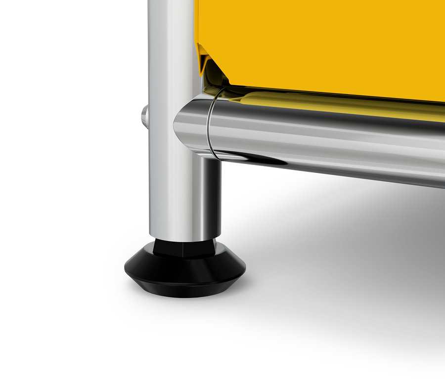 Detal żółtego mebla z chromowaną nogą i czarną stopką.