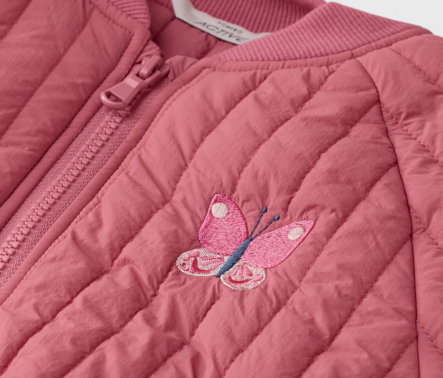 Zbliżenie na pikowaną, różową kurtkę z zamkiem błyskawicznym i haftowaną aplikacją motyla.
