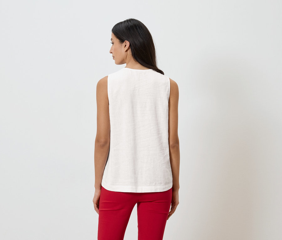 Kobieta od tyłu w bluzce bez rękawów i czerwonych spodniach na białym tle.