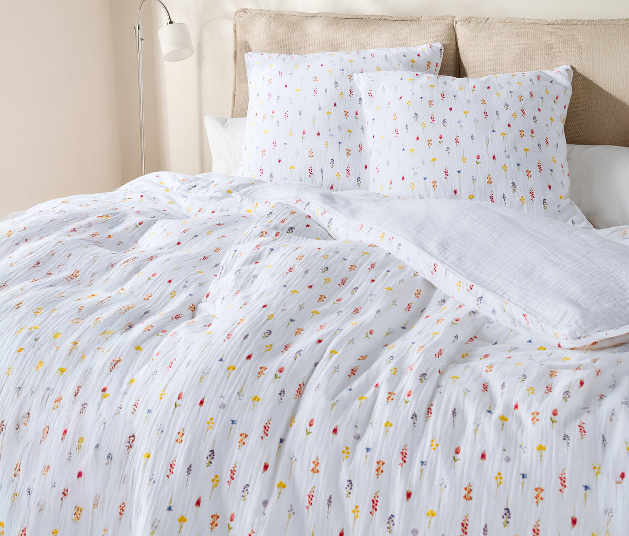 Zbliżenie łóżka z białą pościelą w kwiaty i poduszkami.