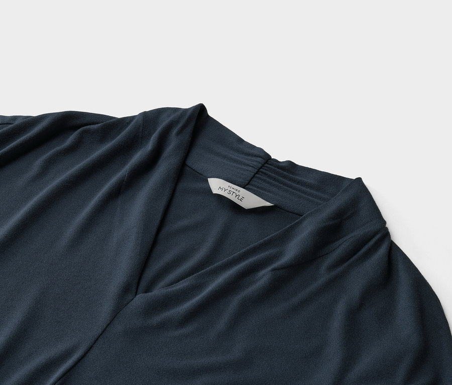 Zbliżenie granatowej bluzki z dekoltem w szpic i metką z napisem „Tchibo My Style”.