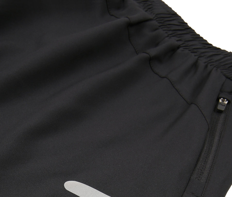 Zbliżenie czarnych szortów z elastycznym pasem, kieszenią na zamek i odblaskowymi paskami.