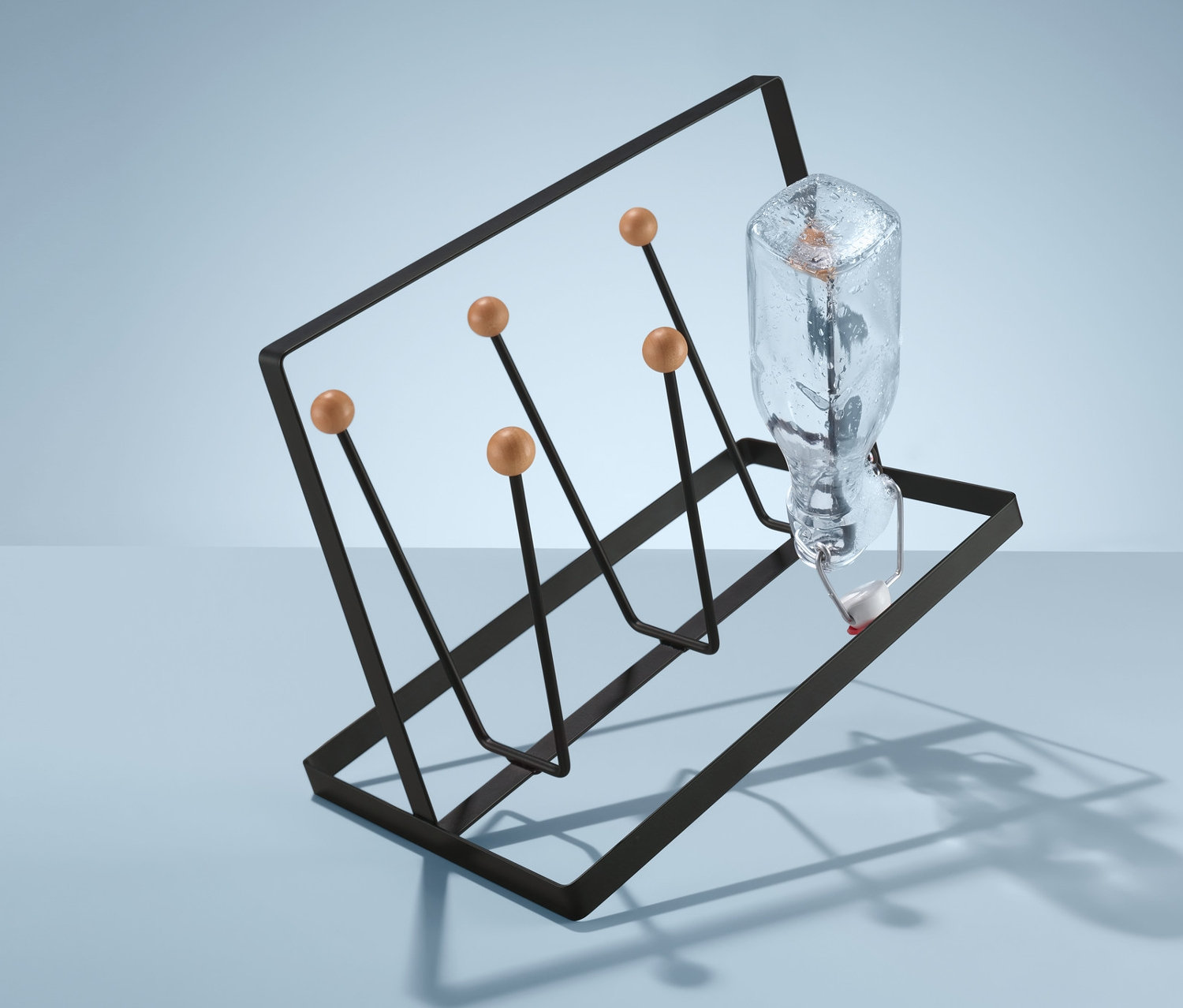 Szklana butelka stoi na stojaku na szklanki i kubki.