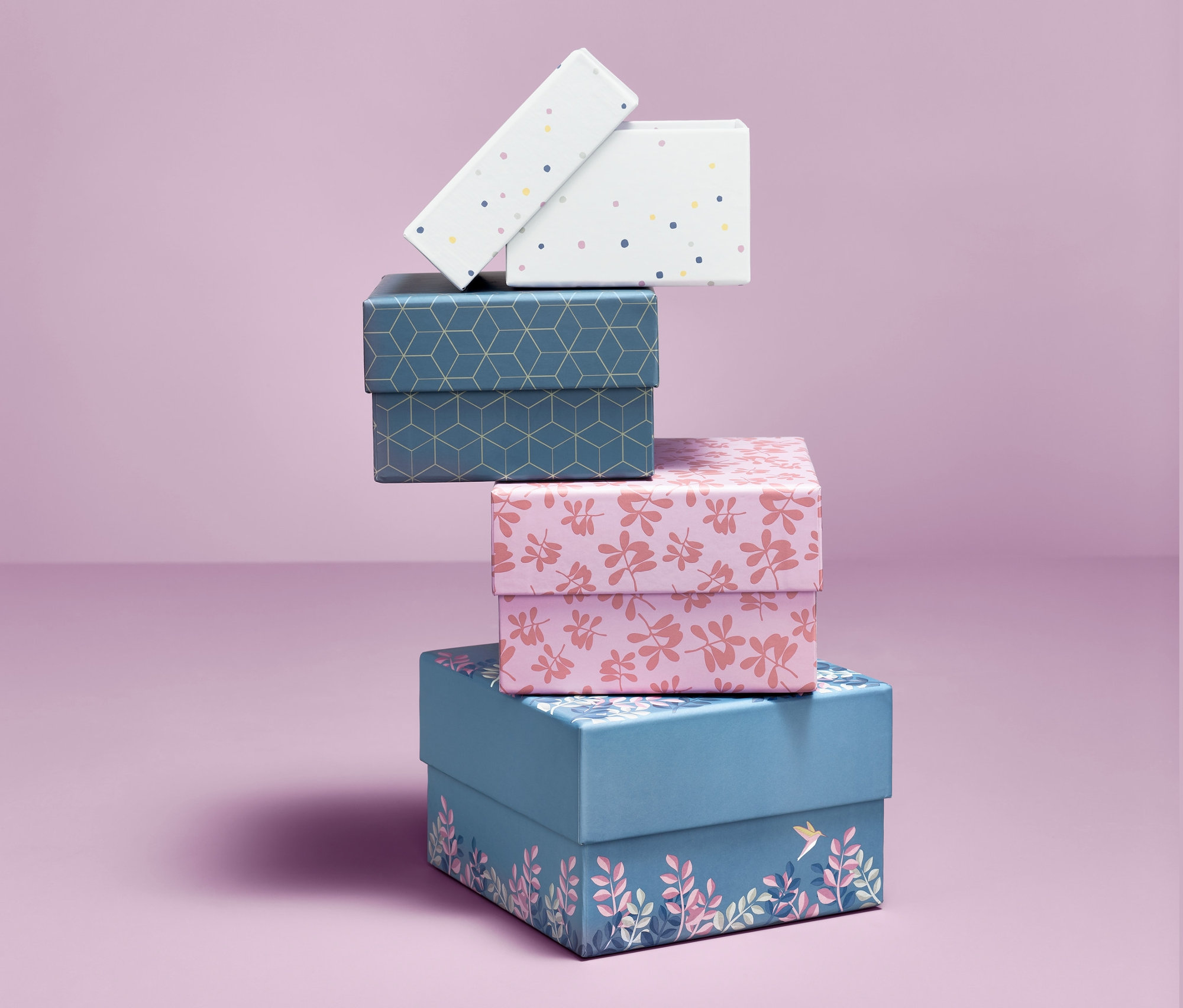 Na fioletowym tle ułożone są ozdobne pudełka, 4 sztuki, o różnych wzorach.