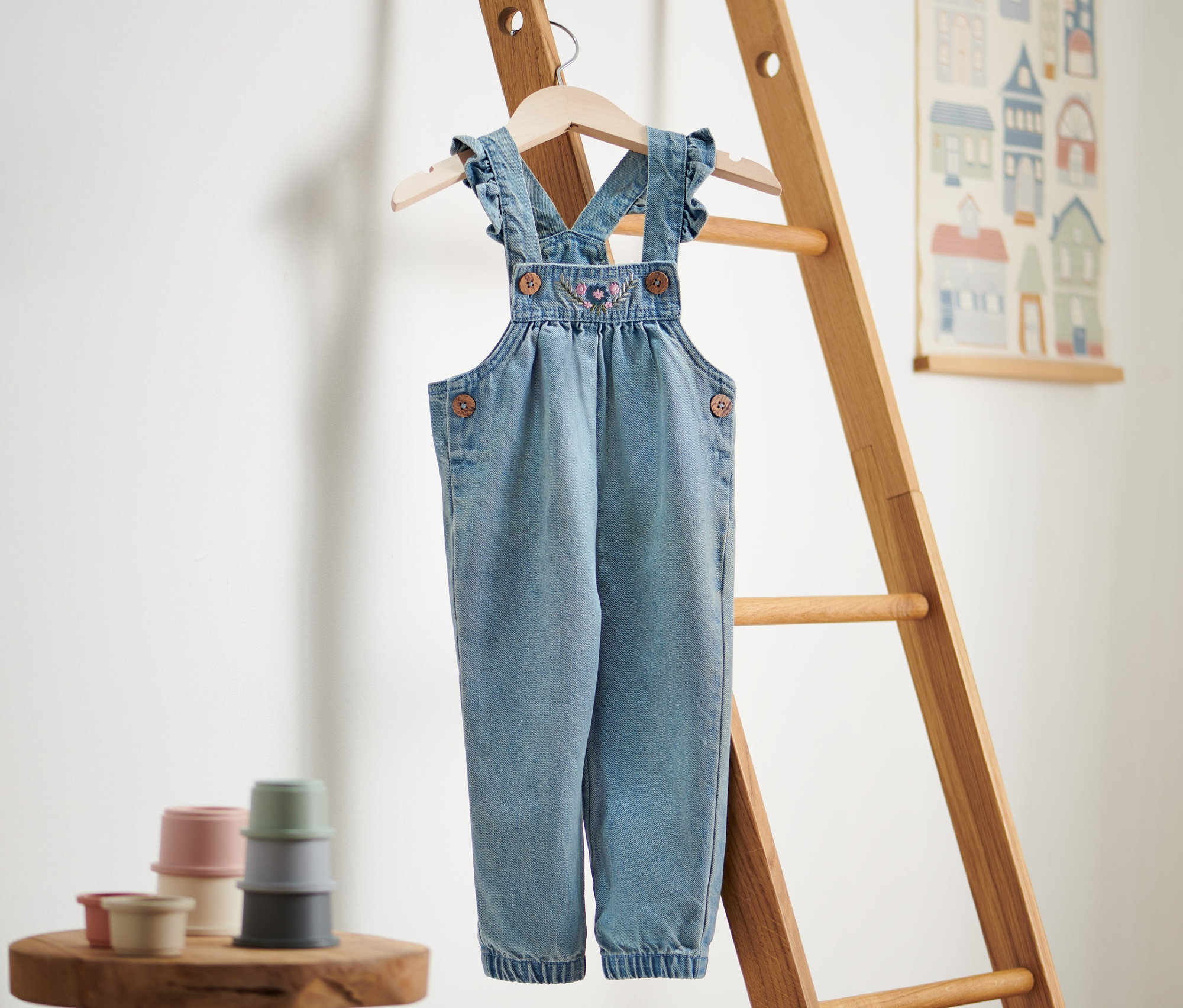 Ogrodniczki dżinsowe wiszą na drewnianej drabinie.